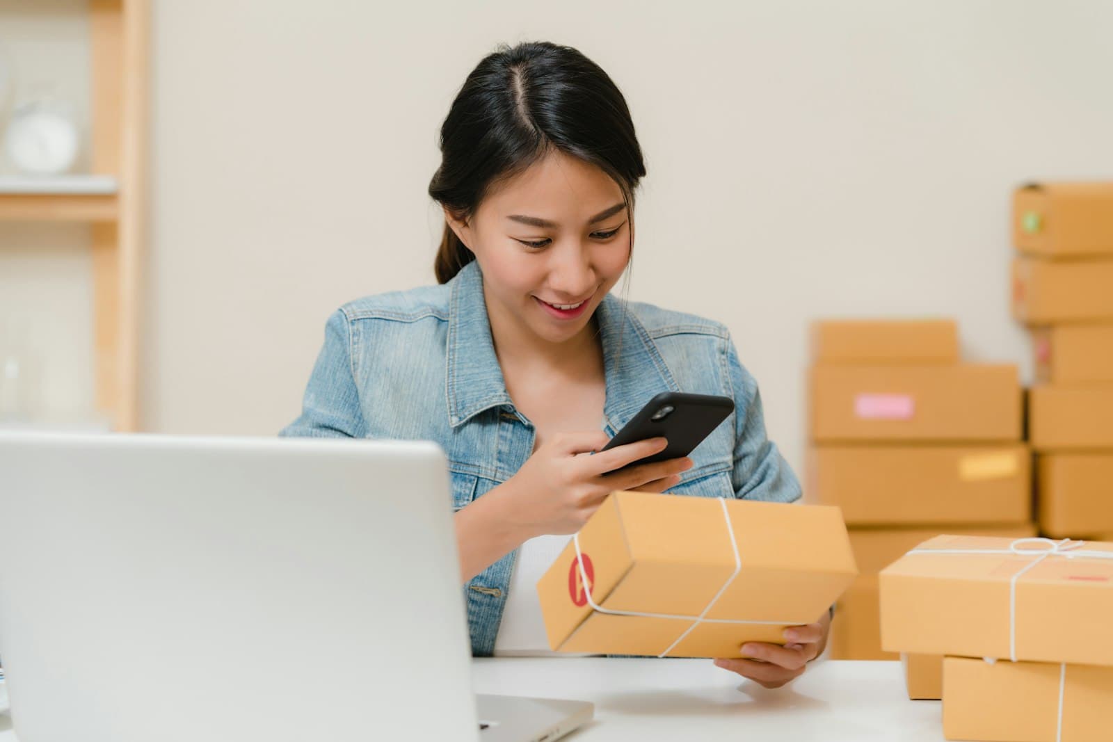Mujer fotografiando con el celular una caja lista para despachar